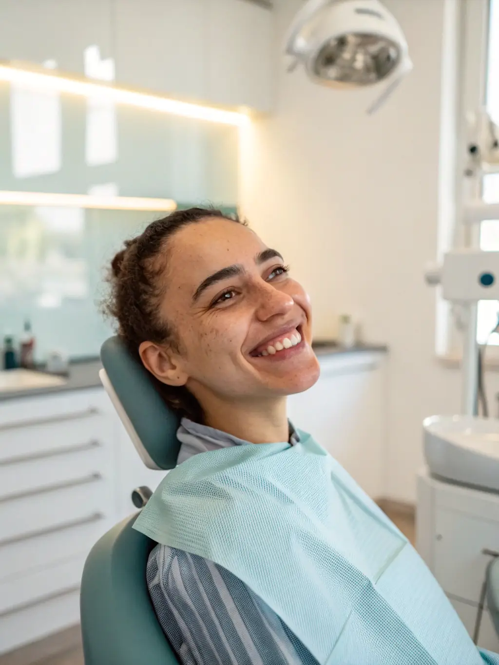 A patient smiling confidently after receiving cosmetic dental treatment, such as teeth whitening or veneers, in a spa-like dental office.
